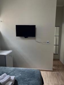 伊塔皮拉Quarto privativo no centro 01的卧室配有壁挂式平面电视。