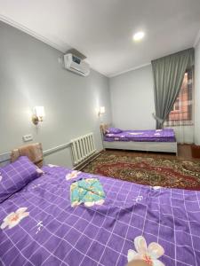 撒马尔罕Family Guest House的客房内的两张床,上面有紫色床单和鲜花