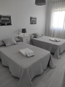 伊扎洛Apartamento Area Pequena Ézaro 2的卧室内的两张床和毛巾