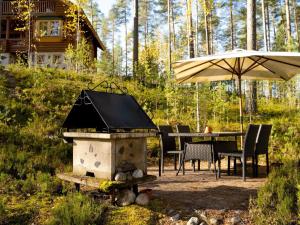 YlämyllyHoliday Home Villa tunturitervakko by Interhome的院子里的带桌子和遮阳伞的烧烤架