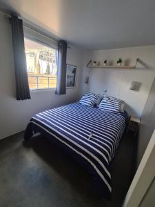 Omessao fil de l'eau的一间卧室配有一张蓝色和白色条纹的床