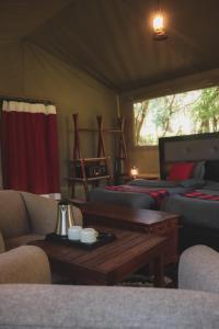 SekenaniDrunken Elephant Mara的客房设有两张床、一张桌子和一张沙发。