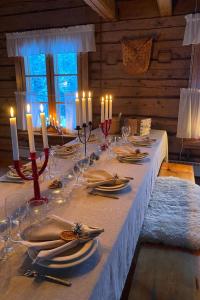 HyrynsalmiHoliday Home Laattajan hirsipirtti by Interhome的长桌,带蜡烛,盘子和餐巾