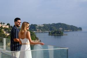 帕拉马Ray Hotel Corfu的男人和女人站在一个俯瞰湖泊的阳台