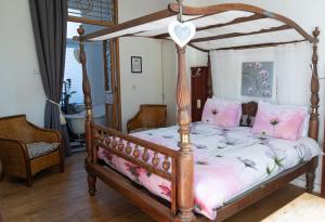 耶尔瑟克B&B Het Oude Postkantoor的一间卧室配有带粉红色枕头的木制天蓬床