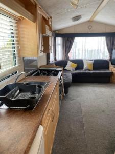 斯凯格内斯Static van on Smallgrove in Ingoldmells的一间厨房和一个客厅,客厅的沙发位于大篷车内