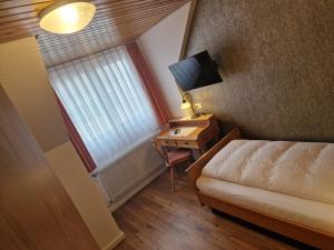 海利根堡霍斯贝恩旅馆的小房间设有一张床和一张书桌及电视