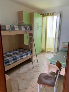 丽都玛里尼SPELU - Appartamento con terrazza fronte mare的客房设有双层床、椅子和桌子。