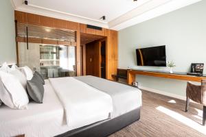 地拉那Select Hill Resort的卧室配有白色的床和电视。