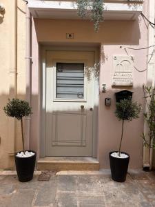 罗希姆诺Smyrni Rethymno Suites的两棵盆栽植物的房子的前门