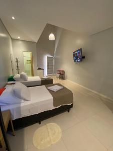 戈亚斯州上帕莱索Pousada Aurora的一间卧室设有两张床,墙上配有电视。