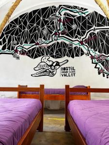RivadaviaHostal Cosmo Elqui的墙上壁画的房间里设有两张床