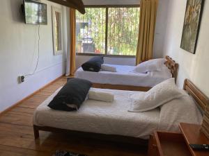 圣地亚哥El Pillan "Travelers" House的带窗户的客房内的三张床