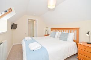 海景城24 Tollgate Cottages的卧室配有一张白色大床和电视。