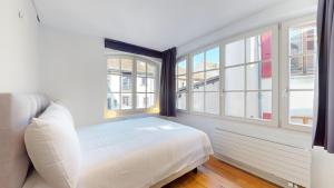 吕特里Charming apartments in the center of Lutry的卧室配有白色的床和窗户。