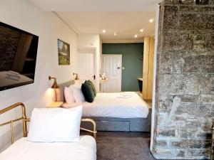 利斯卡德Wheal Tor Hotel & Glamping的一间卧室设有两张床和石墙