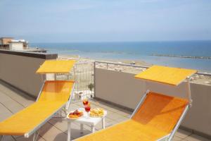 里米尼Activ Hotel Salsedine的一个带两把椅子和一张桌子的阳台和一个海滩