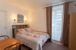 巴黎理想酒店的一间卧室配有一张床、一张桌子和一个窗户。