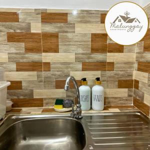 马里韦莱斯Malunggay Apartments的厨房水槽,墙上装有两瓶白色的瓶子