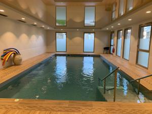 里摩日Domitys Villa Kera的大型室内游泳池设有木地板和窗户