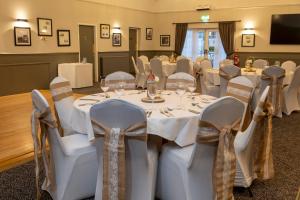 科尔维尔Charnwood Arms的宴会厅配有白色的桌椅