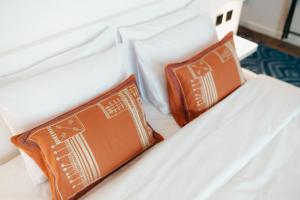 迪拜Shada Hotel - فندق شدا的一张带两个橙色枕头的白色床
