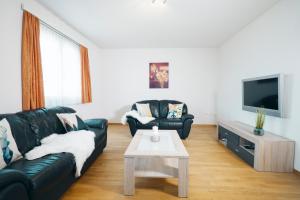 艾姆敦Schwendihaus Apartment的客厅配有黑色真皮沙发和电视