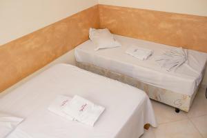 阿帕雷西达Pousada Santa Cruz的小客房内的两张床,配有白色床单