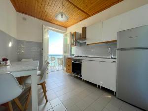 韦尔纳扎Families or Groups 3 Terrazzi Apartment on Sea的厨房配有冰箱和桌椅