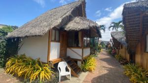 洛佩斯港Zutalu - Playa Sur的茅草屋顶和户外椅子的房子