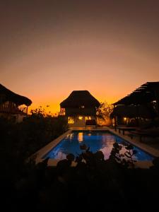 Salina de ReyKite Eco House的日落时分在度假村的游泳池上