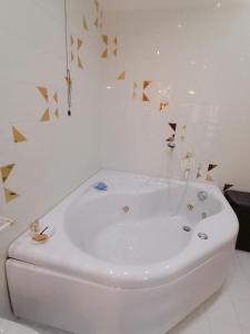 阿科Appartamento Meridiana的白色浴室设有白色浴缸,浴室设有金色三角形