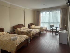 科恰班巴Hotel Oblitas的酒店客房设有三张床和一张桌子