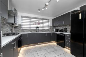 卢顿Contractors Dream~POOL TABLE~Close to Luton Airport~Three Double Bedrooms的厨房配有黑色橱柜和黑色冰箱。