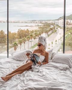 伏罗拉Yacht Hotel的坐在床上读书的女人