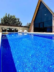 盖贝莱Gabala Twin A Frame Villas的一座大游泳池,位于房子前面,铺有蓝色瓷砖