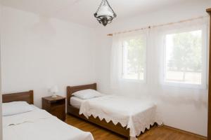 PisarovinaKrašograd的白色客房的两张床,设有两扇窗户
