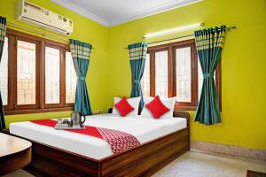 加尔各答Flagship Himgiri Guest House的一间卧室设有一张带绿色墙壁和窗户的床。