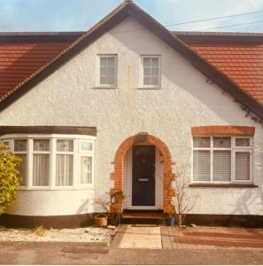 AshfordGorgeous Cosy home 2 Miles from Heathrow Airport的白色的房子,有门和窗户