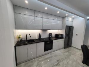 奥尔什丁JURA PARADISE的厨房配有白色橱柜和黑色冰箱。