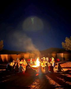梅尔祖卡Overnight Desert Camp的一群人晚上坐在火炉旁