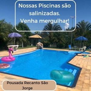 阿瓜斯迪林多亚POUSADA RECANTO SÃO JORGE的度假村的游泳池,上面标有读过nosas pisas的标志