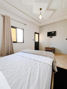 达赫拉Hotel Ahmed Ali的卧室配有白色的床和平面电视。