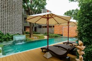清迈Proud Phu Fah Muang Chiang Mai的游泳池旁的遮阳伞和椅子