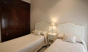 塞维利亚马斯特兰扎酒店的一间卧室设有两张床和一张桌子上的台灯。