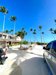 蓬塔卡纳cozy apartment near the beach los corales punta Cana.的棕榈树海滩上停泊的汽车