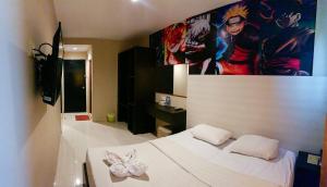 巴淡岛中心OS Hotel Batu Aji Batam的卧室配有白色的床和墙上的绘画作品