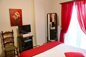 阿吉亚玛丽娜Sanctuary Villa in Vagia, Aegina的一间卧室配有一张带红色窗帘的床和电视。