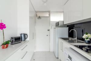 悉尼Studio with Stunning Views and Free Parking的白色的厨房配有水槽和冰箱