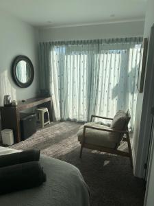 但尼丁Guest Suite St Clair Beach的一间卧室配有一张床、一把椅子和镜子